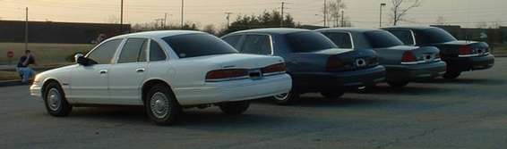 White 1998 Ford Crown Victoria parked in a line with other sedans