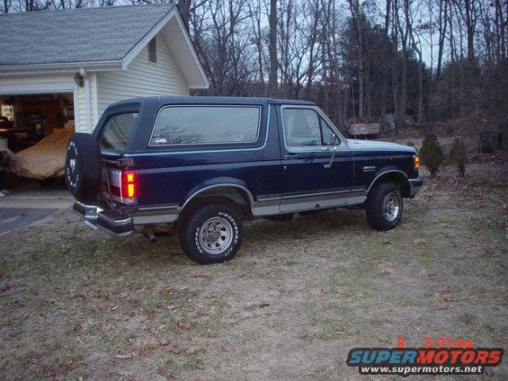 Dark blue 1990 Ford Bronco parked in a driveway next to a garage