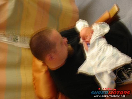 Man holding a baby, blurred motion. Watermark reads SUPERMOTORS