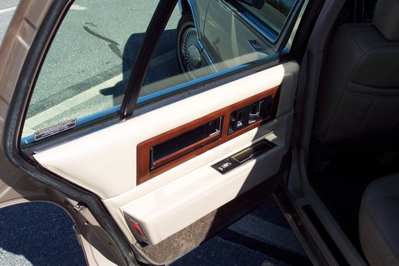 Interior door panel with wood trim and window. Another car's wheel is visible through the window