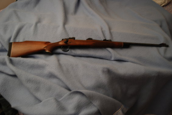 Wooden rifle with a blued barrel and action, resting on a blue blanket