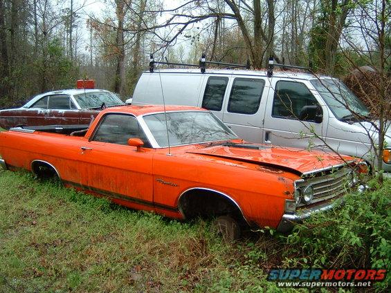 Orange Ford Ranchero with black side stripe, dented hood, and missing front wheel