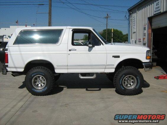 White Ford Bronco with lifted suspension and off-road tires parked on concrete