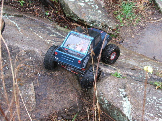 Blue RC rock crawler truck with large tires climbing over rocks