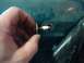 1996 Ford Bronco - A hand holds a bolt and washer near a hole in a teal surface, with a black object visible to the right.