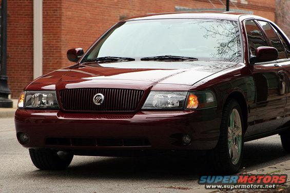 Front view of a dark red Mercury Grand Marquis with a vertical grille and chrome wheels