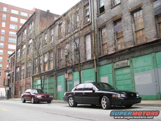 Black 2003 Mercury Marauder and a maroon sedan parked on a street in front of old brick buildings