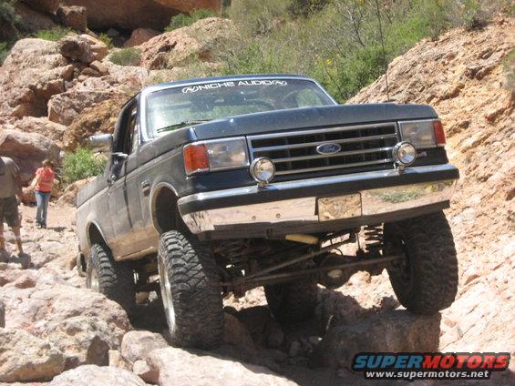 Dark blue Ford F-Series truck with off-road tires navigating rocky terrain