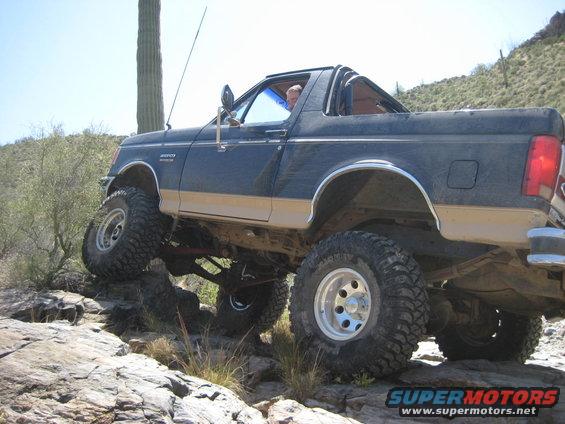 1991 Ford Bronco climbing over rocks on a desert trail