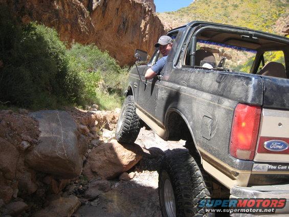 1991 Ford Bronco navigating a rocky off-road path with a driver visible