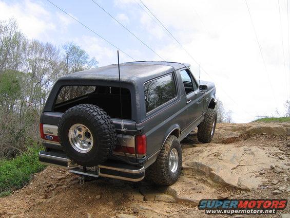 Dark gray Ford Bronco with spare tire on rear, driving on rocks