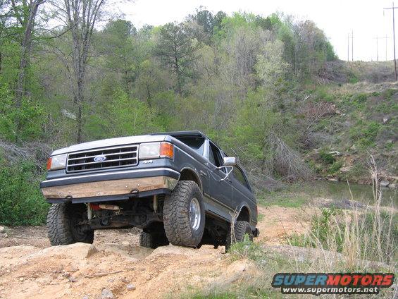 1989 Ford Bronco on a dirt trail with large tires, front wheels elevated