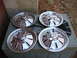 1964 Chevrolet Corvette - Set of four chrome hubcaps, each the iconic Corvette flags emblem, are displayed on an outdoor unit.