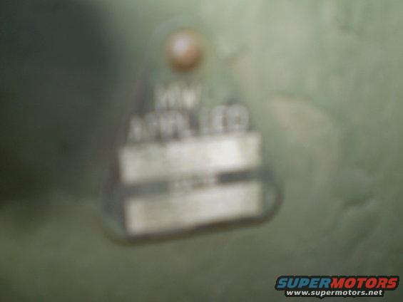 Metal tag with text, attached to a green surface