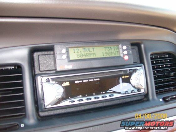 Car dashboard showing a JVC stereo and a digital display with voltage, RPM, and temperature readings