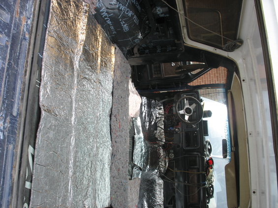 Vehicle interior with soundproofing material on the door and floor, showing the dashboard and steering wheel