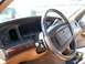 1995 Mercury Grand Marquis - The interior of a 1995 Mercury Grand Marquis shows a tan dashboard with wood trim, digital gauges, and a large steering wheel.