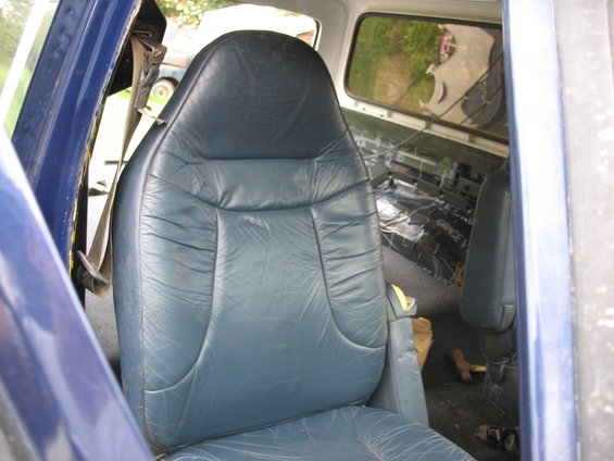 Blue leather seats inside a vehicle, with sound deadening material visible in the rear
