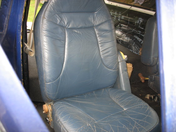 Blue leather seats inside a vehicle, with sound dampening material visible on the floor and walls