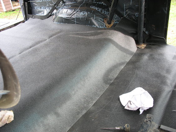 Interior floor of a vehicle with new carpet and sound deadening material installed on the rear floor and behind the seats