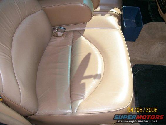 Close-up of tan leather car seat with visible stitching and a shadow on the cushion