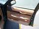 1995 Mercury Grand Marquis - The interior door panel of a car features tan fabric, wood accents, and power window controls.