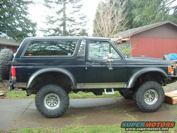 1989 Ford Bronco parked on a driveway, side view. Lifted suspension and large tires