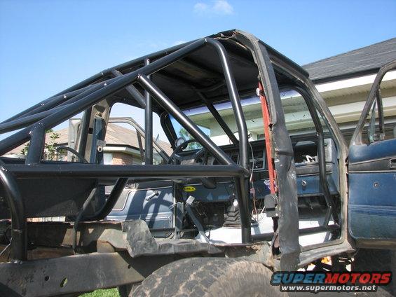 Interior view of a vehicle with a custom roll cage, showing the dashboard and open doors