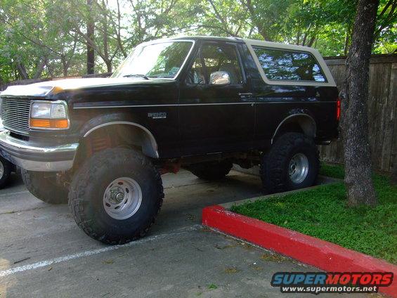 1992 Ford Bronco parked on pavement with grass and trees