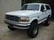 1992 Ford Bronco - A white 1992 Ford Bronco is shown from a three-quarter front angle, lifted with large tires.