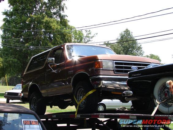 Brown 1989 Ford Bronco on a car carrier, front 3/4 view