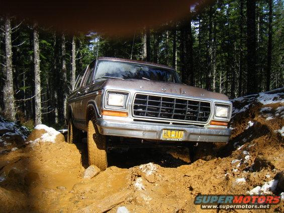 1978 Ford Bronco driving through mud on a wooded trail