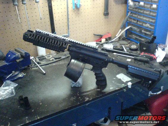 Assault rifle with drum magazine on workbench