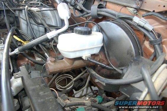 Engine bay showing brake master cylinder and various hoses and wires