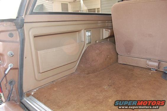Back cargo area of a brown SUV with tan door panel and carpeted floor