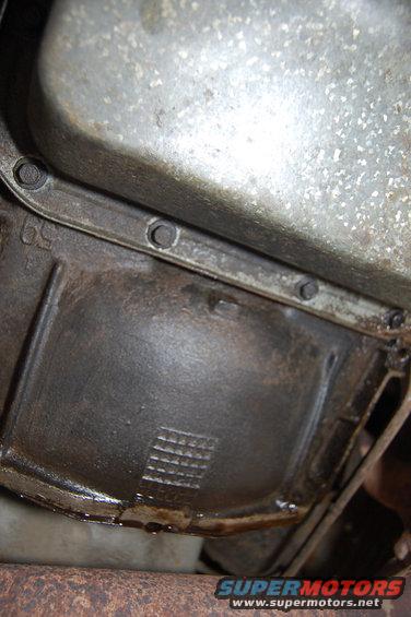 Transmission pan with visible oil leak and casting marks