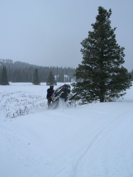 Snowmobile on its side in the snow with a person next to it
