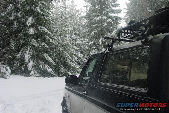 Black Ford Bronco with roof rack in snowy forest