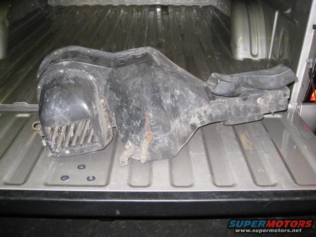 Black plastic HVAC blower motor housing sitting in a truck bed