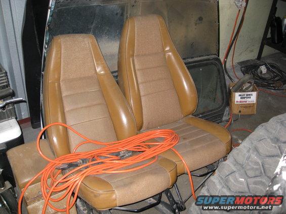 Brown car seats with orange extension cord, in a garage with a tire and box