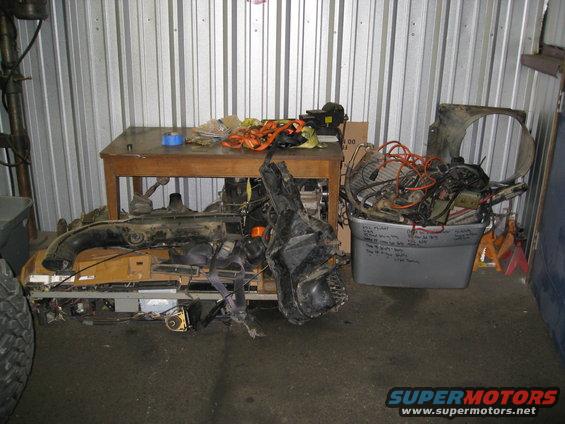 Parts piled on a table and in a bin inside a metal-walled storage unit