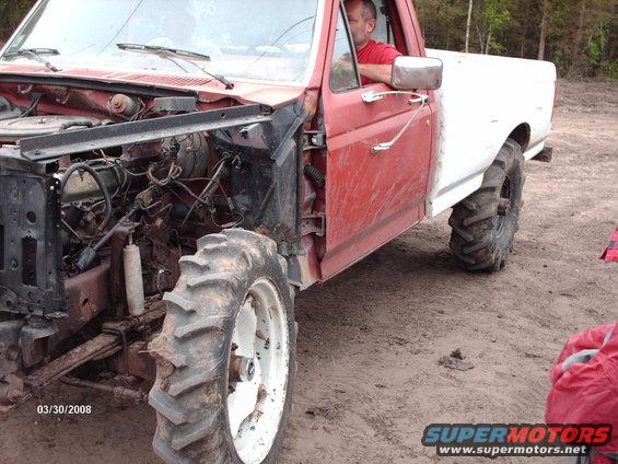 Red and white pickup truck with exposed engine and large tractor tires