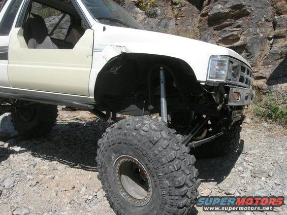 White 1989 Toyota pickup truck modified for off-roading with large tires and lifted suspension