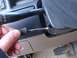 1996 Ford Bronco - A close-up view of a hand adjusting a screw on the steering column, near the turn signal stalk.