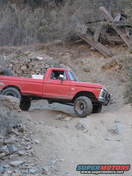 Red pickup truck on a dirt trail, front grille visible