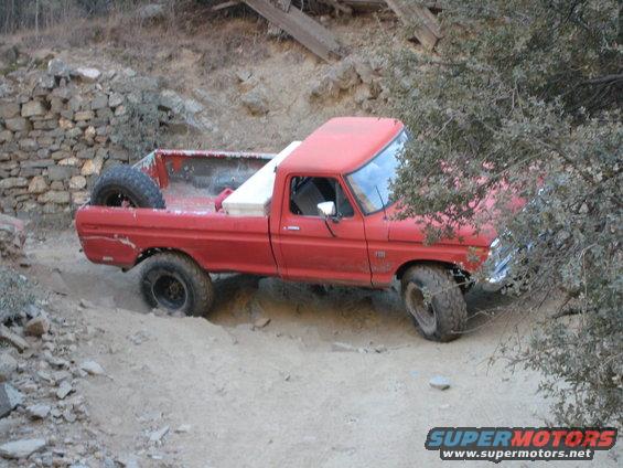 Red 1974 Ford F-250 off-roading on a dirt path