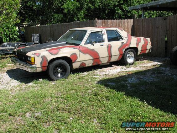 Tan and red camouflage sedan parked in a yard