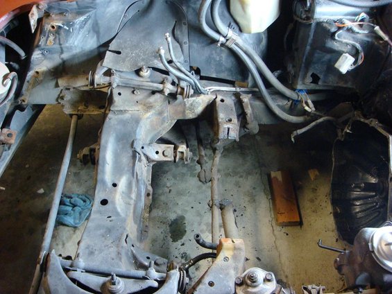 Disassembled car frame with suspension parts and brake lines visible