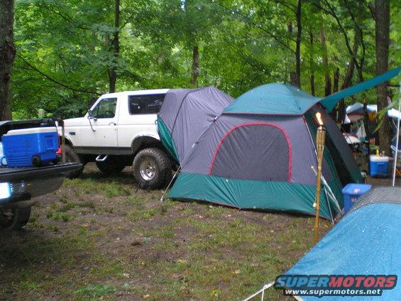 White Ford Bronco parked next to a campsite with tents