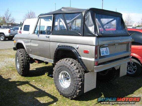 Modified Ford Bronco with soft top and large off-road tires, rear 3/4 view